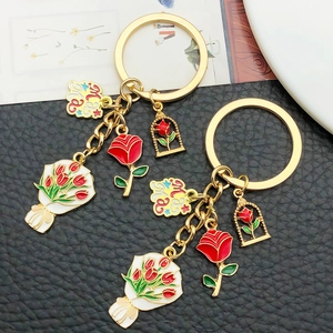 Detailed macro view of two gold Mama keychains with red tulip and rose enamel charms