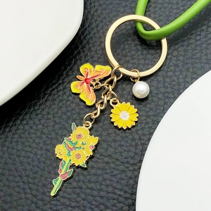 Macro detail of enamel sunflower and butterfly keychain with pearl on leather background