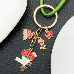 Close-up of golden MAMA keychain with red rose and carnation charms on black leather