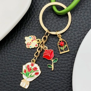 Detail of mama charm keychain with red tulip bouquet and rose pendants on leather surface