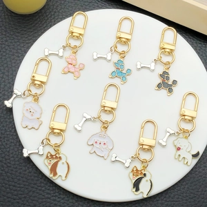 Porte-clés chien en émail avec charms os présentés sur un plateau d'exposition blanc