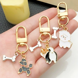 Vue détaillée de porte-clés chien en émail avec pendentifs os et fermoirs dorés