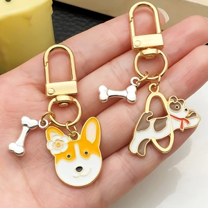 Cartoon dog enamel keychains with Corgi and puppy charms held in hand for scale