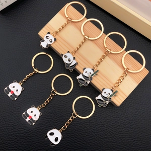 Detailed view of seven enamel panda keychains with golden alloy rings on a wooden display