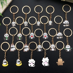 Collection of 20 cute cartoon panda keychains with gold metal rings on black leather background