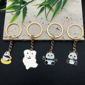 Detail of four cute cartoon panda keychains with gold alloy rings on marble