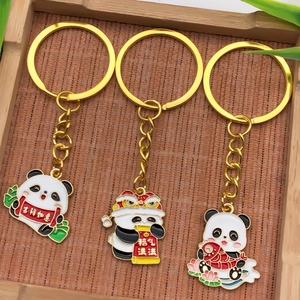 Detail of three panda enamel keychains with lion dance and koi fish motifs