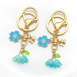 Close-up of cherry blossom and lily of the valley enamel keychain with golden bee charm