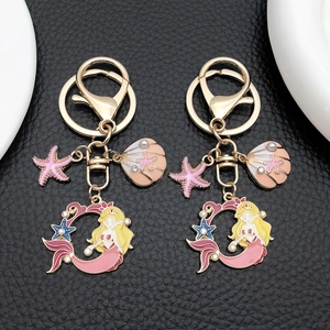 Détail du porte-clés sirène rose avec breloques coquillage et étoile sur cuir noir
