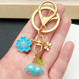 Golden keychain with blue cherry blossom, bee charm and lily of the valley beads