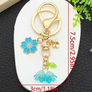 Golden keychain with blue cherry blossom, enamel bee, and gradient lily of the valley