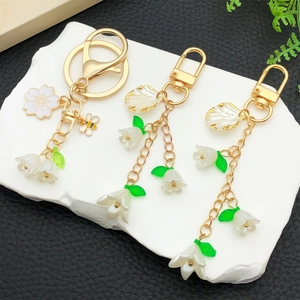 Acrylic lily of the valley and bee keychain pendant set on a white stone display