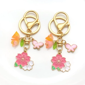 Détail de breloques fleur de cerisier et papillon rose sur un porte-clés doré