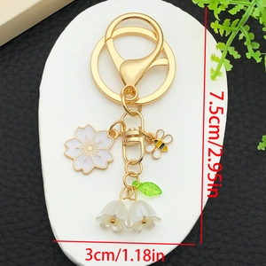 Floral keychain featuring white cherry blossoms, honey bee and lily of the valley charms