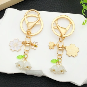 Porte-clés doré avec fleurs de cerisier, muguet, abeille blanche et breloques de feuilles