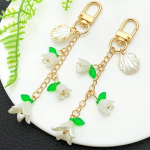Eleganter weißer Maiglöckchen-Schlüsselanhänger mit goldenem U-Verschluss und grünen Blättern
