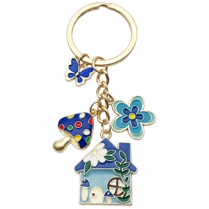 Golden keychain with blue butterfly, mushroom house, and floral enamel pendants