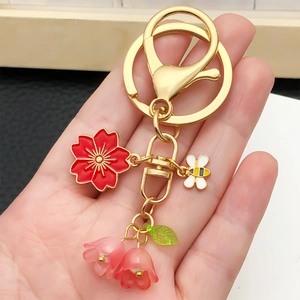 Goldener Schlüsselanhänger mit Kirschblüte, Maiglöckchen und Bienenanhänger in Rot
