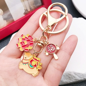 Detail showing cartoon horse and firecracker charms on a gold zodiac keychain