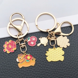 Detailed close-up of golden zodiac horse keychain with red apple and firecracker charms