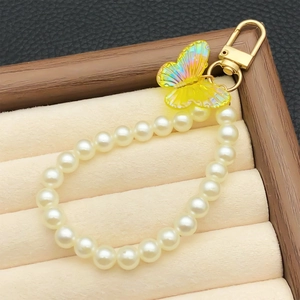 Pendentif papillon en acrylique jaune avec perles blanches et fermoir doré sur plateau