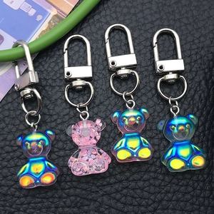 Detail of four colorful gradient resin bear keychains on black leather background