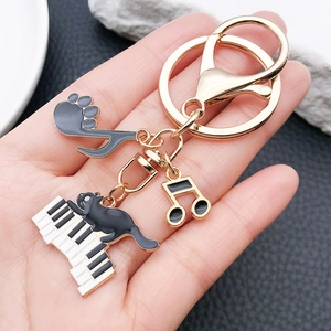 Detailed macro view of piano and black cat keychains held in hand for size visualization