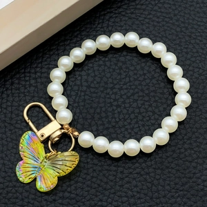 Détail macro d'un cordon en perles avec un pendentif papillon en acrylique iridescent