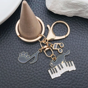Detail of golden keychain with black enamel piano cat and musical note charms