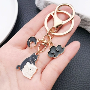 Close-up of cute black cat reading on books keychain charm with moon and cloud detail