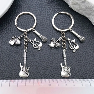 Detailed view of antique silver music keychains with guitar and drum charms on leather