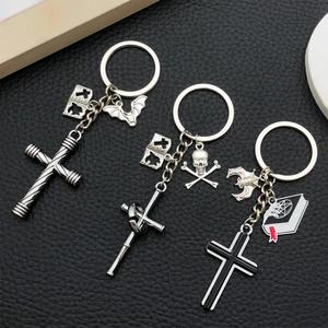 Detail of Gothic keychains with cross, bat, and skull charms on black leather background