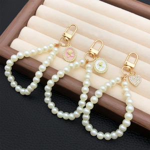 Elegant pearl keychain set with rose medallions and heart pendant on jewelry display
