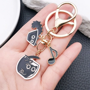 Detailed close-up of cartoon black cat keychain set held by hand with music note charms