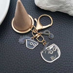Detailed close-up of a golden zinc alloy keychain featuring black cat and music note charms