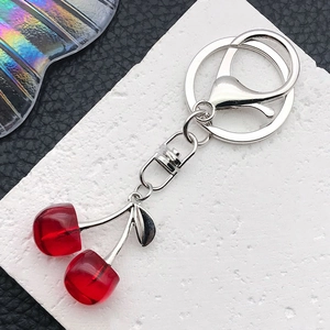 Close-up of translucent red cherry charms with silver metal lobster clasp and leaf detail