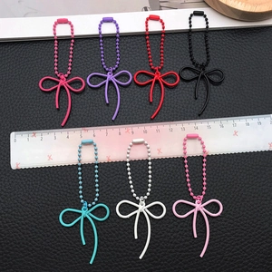 Set of seven colorful alloy bow pendants with beaded chains displayed against a dark texture