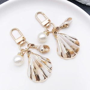 Detailed macro of golden seashell and pearl keychains with glossy resin finish