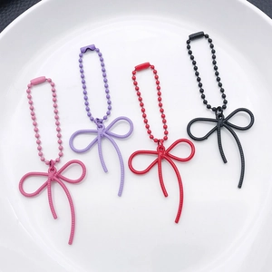 Detail of colorful matte finish alloy bow charms with matching beaded chains on a white plate
