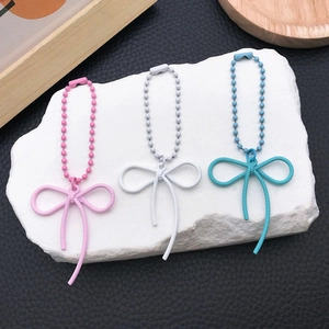 Close-up of alloy bow pendants in pink white and blue with matching bead chains