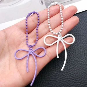 Detailed view of purple and white textured alloy bow pendants with matching ball chains