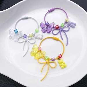 Close-up of colorful resin bear and butterfly bead keychains on a white ceramic tray