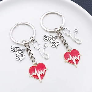 Silver stethoscope and ambulance keychain with red heart ECG pendant on white plate