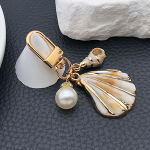 Marine style keychain with acrylic sea shells and pearls on black leather background