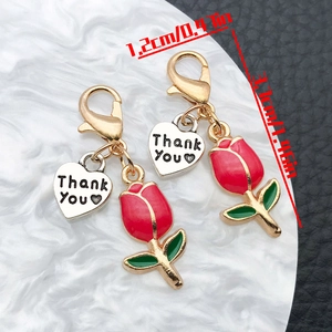 Detailed macro view showing a red enamel tulip pendant with heart tag and lobster clasp