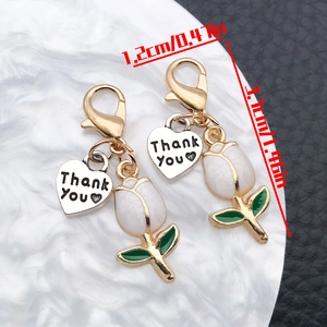 Detailed view of white tulip charm with lobster clasp and Thank You heart pendant
