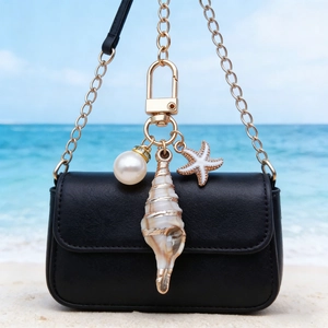 Detail of marine seashell and starfish charms attached to a luxury black leather handbag