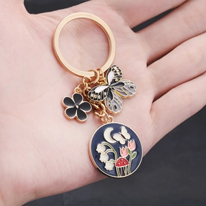 Goldener Schlüsselanhänger mit Schmetterling und Pilzanhängern in der Hand