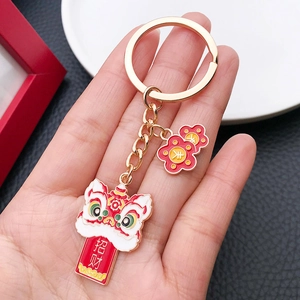 Close-up of Chinese lion dance keychain with red Zhaocai fortune tag and gold metal chain