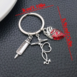 Detail showing medical syringe and stethoscope charms on a vintage silver keychain